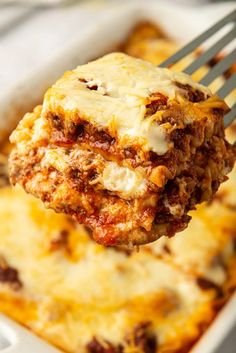 a fork is holding up a lasagna casserole with meat and cheese