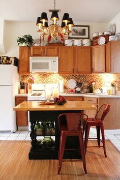 a kitchen with wooden cabinets and white appliances in the center is lit by candle lights