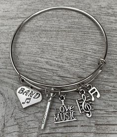 a silver bracelet with music charms on it and a heart shaped keychain that says, love music