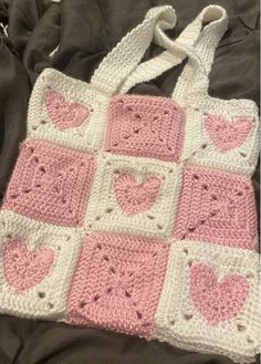 a pink and white crocheted bag sitting on top of a bed