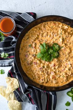 a tortilla dish in a black skillet with cilantro and jalapenos next to it