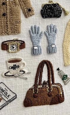 several different types of handbags and purses on a white tablecloth with embroidered details