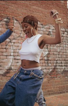 two women are dancing together in front of a brick wall with graffiti on the walls