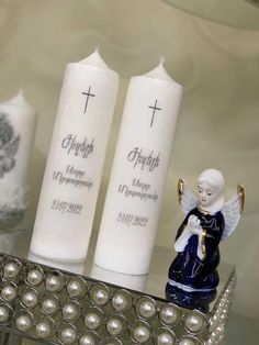 two candles with angels on them sitting next to each other in front of a silver tray