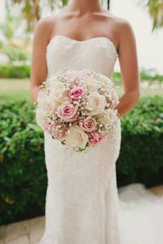 a woman in a wedding dress holding a bridal bouquet with pink and white flowers