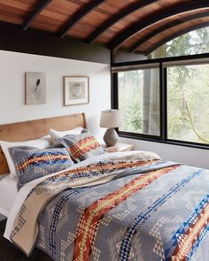 a large bed sitting under a window next to a lamp