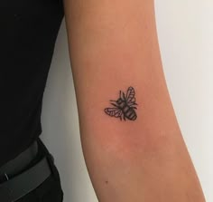 a woman's arm with a small tattoo of a bee on the back of it