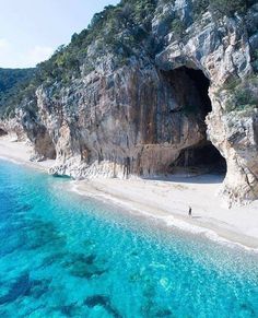 an aerial view of a beach with clear blue water and cliffs on the shore,