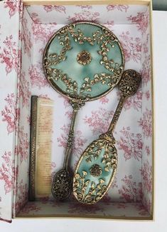 an open box with two spoons and a comb in it