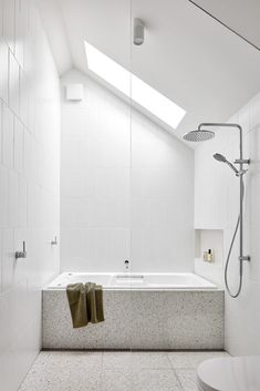 a white bathroom with a skylight above the bathtub