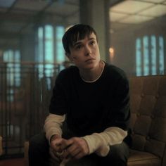 a young man sitting on top of a couch holding a remote control in his hand