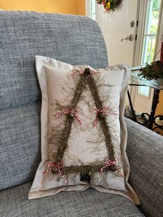 a christmas tree made out of twigs on a pillow sitting on a couch in front of a door