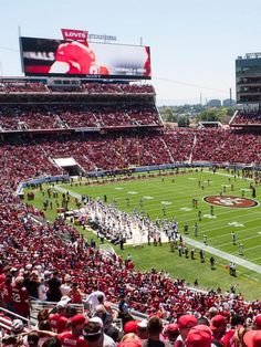 a football stadium filled with lots of people on the field and fans in red shirts