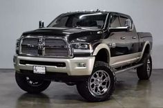 a black and silver truck is parked in a room with concrete floors, white walls and gray flooring