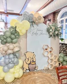 a baby shower sign surrounded by balloons and honeycombs in a room with brick floors