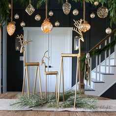 two golden deer statues sitting on top of a wooden table next to christmas decorations and greenery