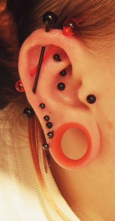 a woman with black and red piercings on her ear