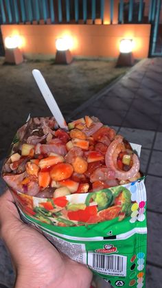 a person holding up a bag of food in front of some lights on the side walk