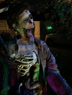 a man dressed up as a zombie holding something in his hand