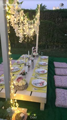 an outdoor table set up for a party with yellow and white plates, napkins and flowers