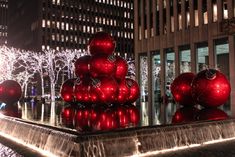 a fountain with red ornaments on it in the middle of a city street at night