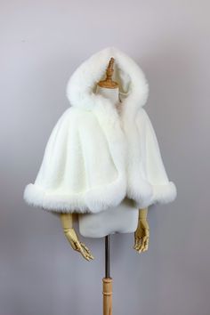 a mannequin's head wearing a white fur coat on a wooden stand