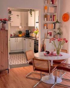 a kitchen and dining room with white cabinets, wood floors and an open floor plan