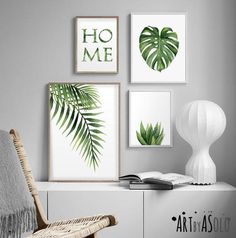 three green leaves are hanging on the wall next to a white chair and bookcase