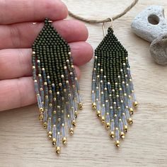 a pair of beaded earrings being held by a hand