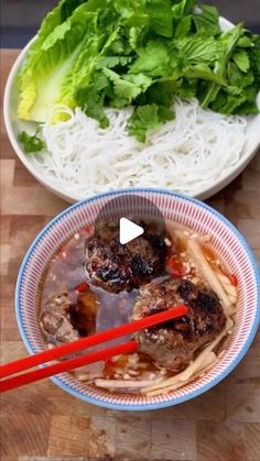 two bowls filled with food and chopsticks on top of a wooden table