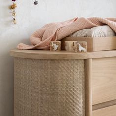 a wooden dresser topped with toys next to a pink blanket on top of a bed