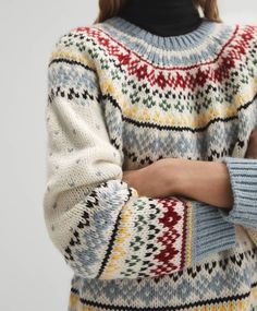 a woman is wearing a sweater with an interesting pattern on it and has her arms crossed