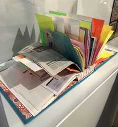 an open book sitting on top of a white table next to a pile of papers