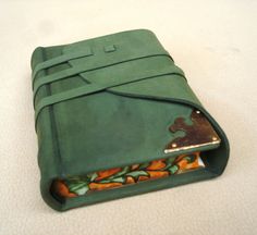 a green leather wallet with puzzle pieces in it on a white tableclothed surface