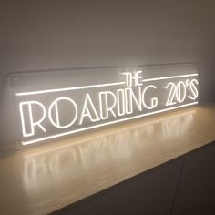 the roaring 20s's neon sign is lit up on a shelf in front of a wall