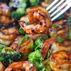 shrimp and broccoli being cooked with a fork