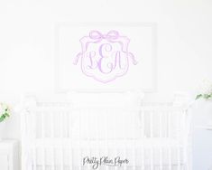 a white crib with a pink monogrammed wall hanging above it