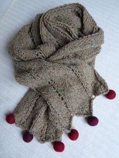 a scarf with pom - poms is laying on the bed