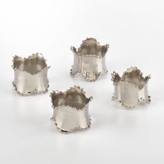 four silver dishes sitting next to each other on a white surface