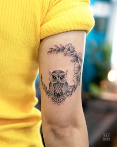 an owl tattoo on the right arm and shoulder is shown in black ink with flowers around it