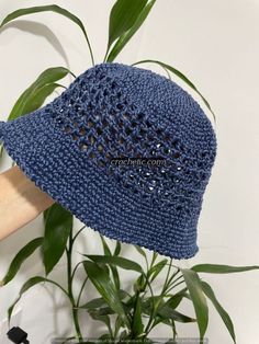 a blue crocheted hat sitting on top of a plant