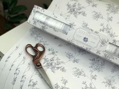 a pair of scissors sitting on top of a table next to a box with floral designs