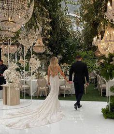 a bride and groom walking down the aisle at their wedding reception in an elegant garden setting