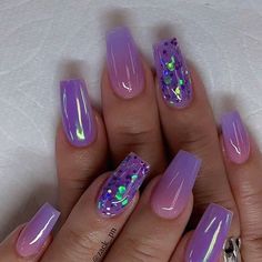 a woman's hand with purple and green nail polishes on her nails,