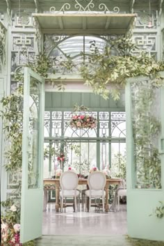 the dining room is decorated with greenery and white chairs, along with pink flowers