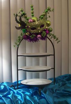 a three tiered cake stand with green and purple decorations on it's sides