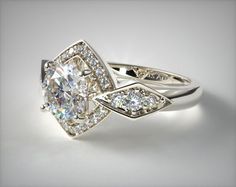 a white gold ring with an oval cut diamond surrounded by smaller round diamonds