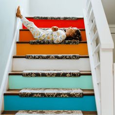 a child laying on top of a set of stairs with their arms up and feet down