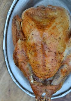 a whole chicken in a bowl on a wooden table