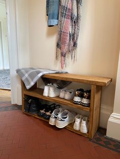 a wooden bench with shoes on it and a blanket hanging from the wall behind it